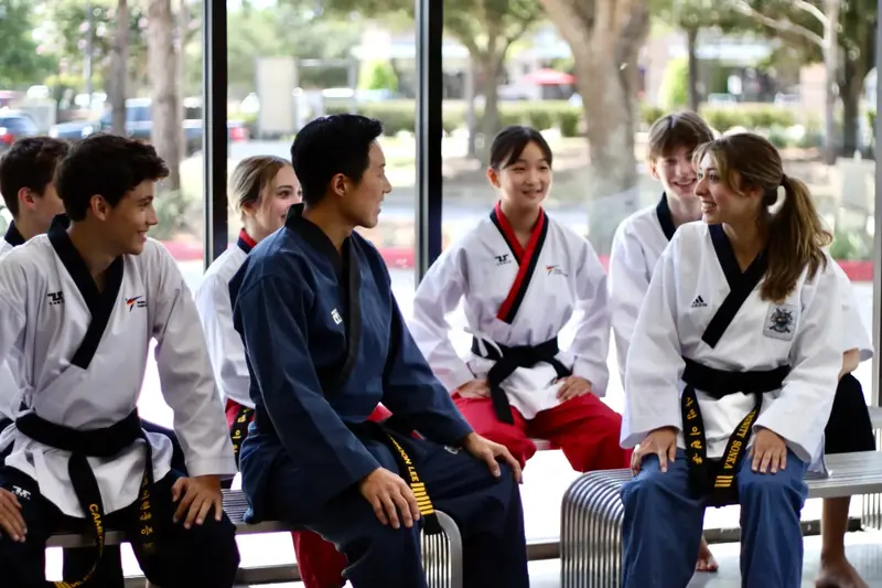 Students in white and navy uniforms sitting together on a bench